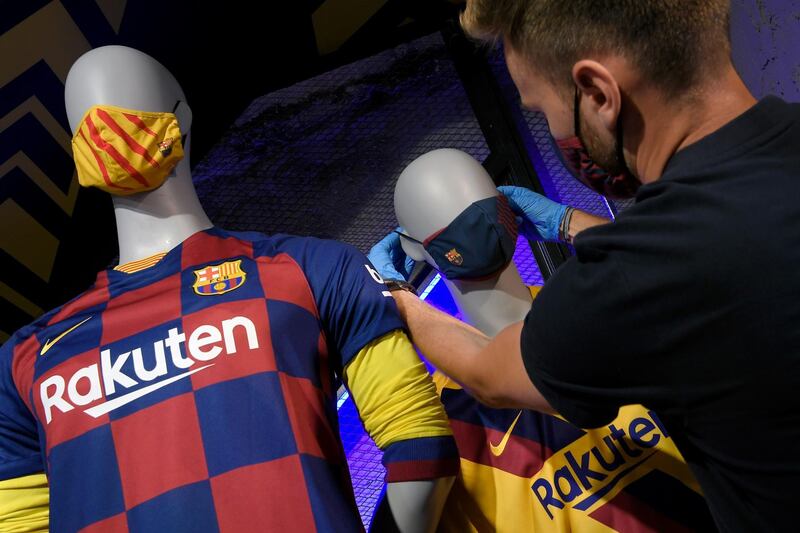 An employee places the mask with the FC Barcelona's logo on a mannequin at the FC Barcelona store. AFP
