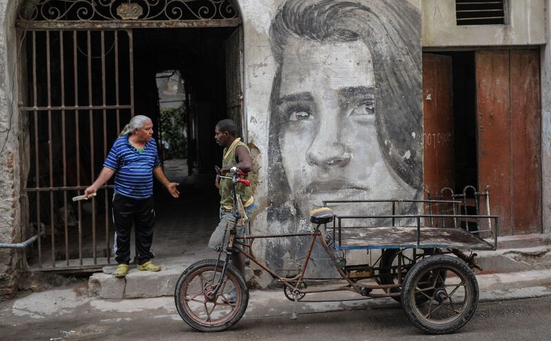 Cubans stand by a mural.