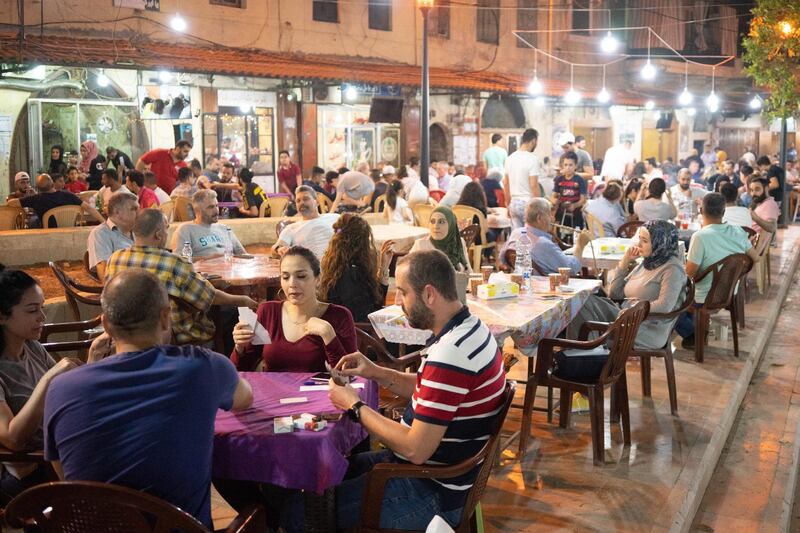 People play cards and smoke shisha at a cafe in Tripoli old souk