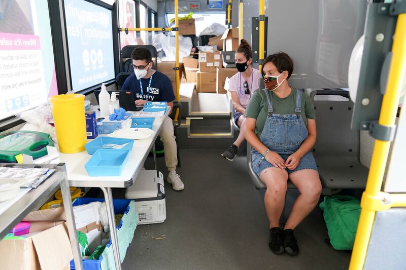 Festival-goers wait to receive a vaccine on board a bus at the Latitude Festival.