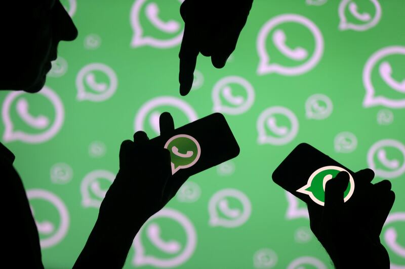 FILE PHOTO: Men pose with smartphones in front of displayed Whatsapp logo in this illustration September 14, 2017. REUTERS/Dado Ruvic/File Photo