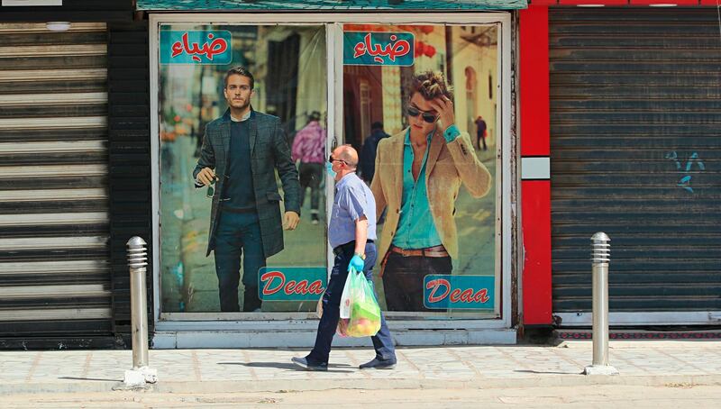 A man walks past shops that are shuttered in Baghdad, Iraq. AP Photo