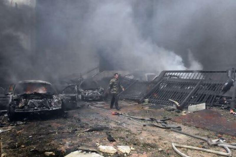 A Syrian security officer walks past burning cars at the scene of a car bomb explosion which rocked central Damascus.