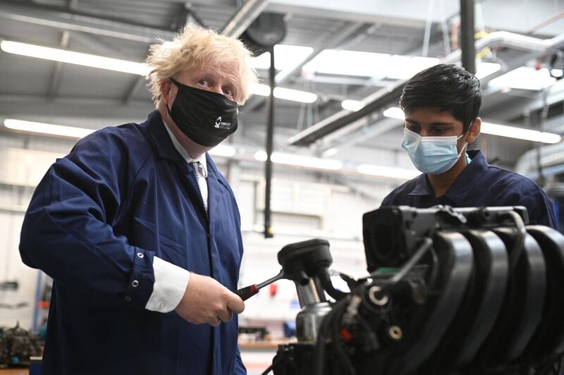 Britain's Prime Minister Boris Johnson (L) assists in an engine repair at the Automotive shop during a visit to Kirklees College Springfield Sixth Form Centre in Dewsbury, northern England on June 18, 2021. / AFP / POOL / Oli SCARFF
