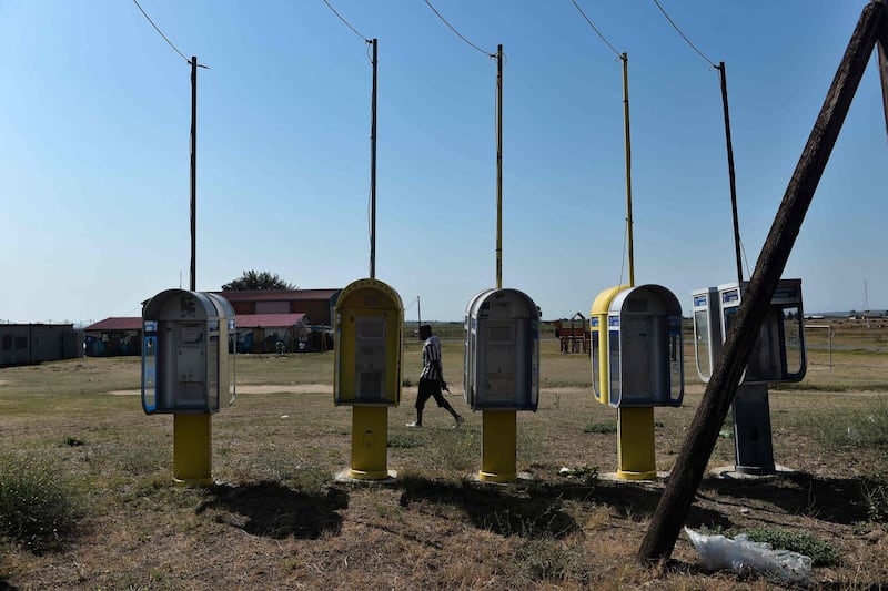 A migrant passes by telephone booths in Nea Kavala camp, near the city of Kilkis, northern Greece.  Some 1000 refugees and migrants were transferred from the Greek island of Lesbos to the Nea Kavala camp under a decision taken by the Greek government at an emergency meeting on August 31.  AFP