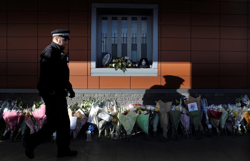 A police officer passes bouquets of flowers at the custody centre where a British police officer has been shot dead in Croydon, south London. Reuters