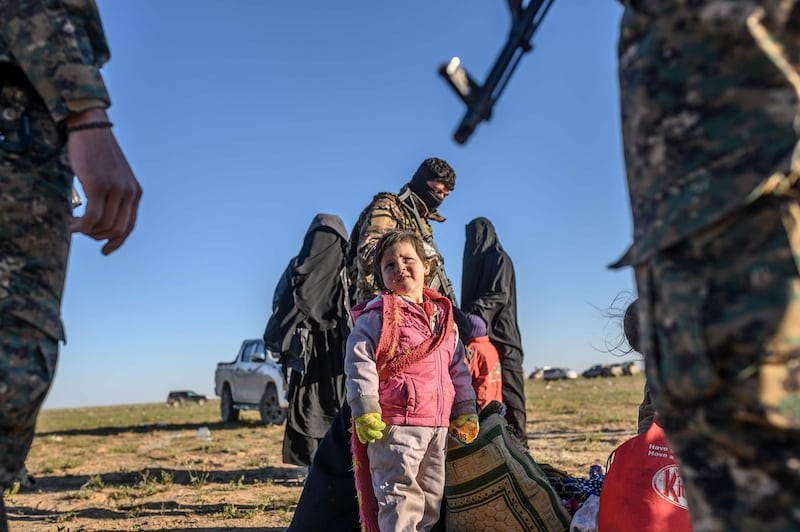 A toddler looks at members of the Kurdish-led Syrian Democratic Forces (SDF) while waiting to be searched, after leaving ISIS's last holdout of Baghouz, in the eastern Syrian Deir Ezzor province. AFP