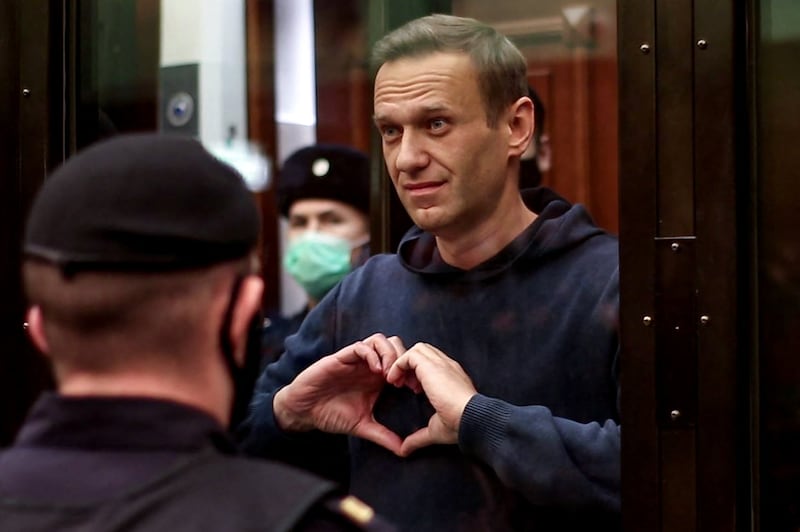 Mr Navalny makes a heart shape towards his wife, Yulia, from inside a glass box in a Moscow court, after being sentenced in 2021. AFP