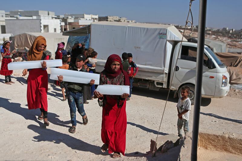 Volunteers provide ice for internally displaced people at the camp in Killi in rebel-held Idlib, Syria.