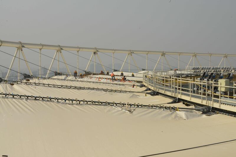 Technicians work on the special 'PTFE' roof that will protect spectators from the elements. AFP