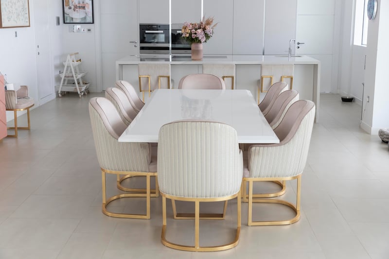 In Caroline Stanbury's Al Barari penthouse, a marble table is paired with chairs that have pink suede seats, leather-upholstered backs and gold legs. Antonie Robertson / The National
