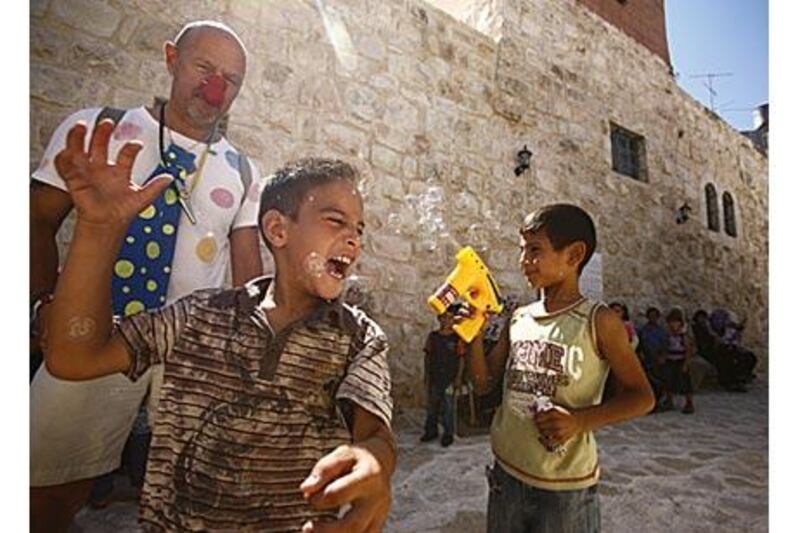 A clown from an international troupe entertains Palestinian children while they wait to be seen by doctors from the Israeli-based mobile medical clinic.