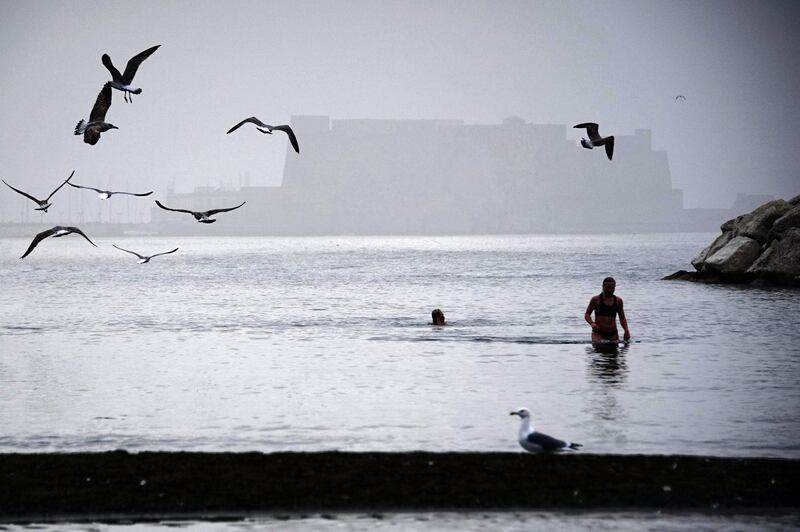 Tourists take a bath in the Naples' gulf, Italy, as fog covers Castel dell'Ovo (the Egg castle). Ciro Fusco / Ansa via AP