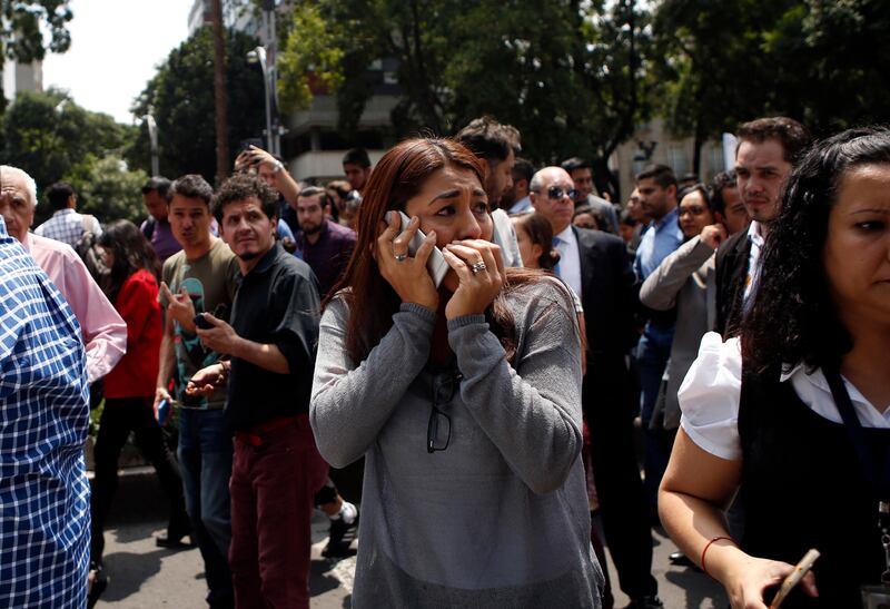 A woman speaks on her cell phone as people evacuated from office building gather in Reforma Avenue after an earthquake in Mexico City. Rebecca Blackwell / AP Photo