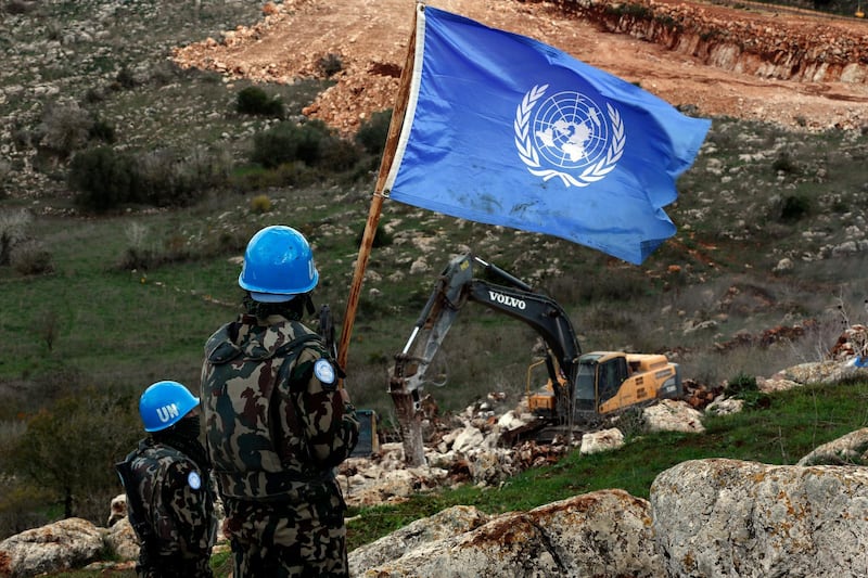 UN peacekeepers hold their flag, as they observe Israeli excavators working near the southern border village of Mays Al Jabal, Lebanon. AP Photo