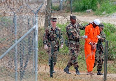 In this February 6, 2002, file photo a detainee is led by military police to be interrogated by military officials at Camp X-Ray at the US Naval Base at Guantanamo Bay, Cuba. AP