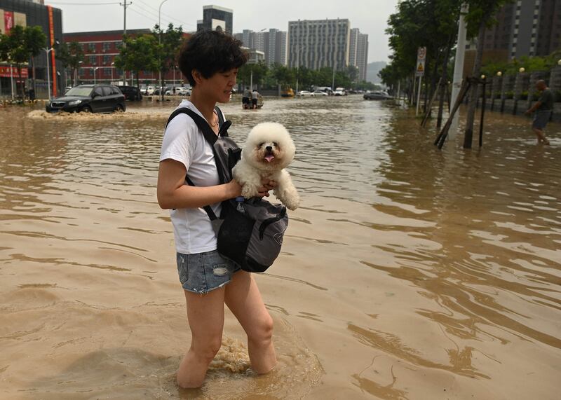 People wade through a flooded street following a heavy rain in Zhengzhou, in China's Henan province.