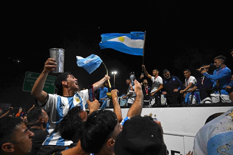 Argentina's players celebrate on board an open-top bus as supporters look on. AFP