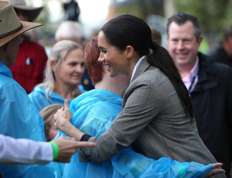 Meghan is embraced by a local woman during a visit to a community picnic at Victoria Park in Dubbo, Australia. AP