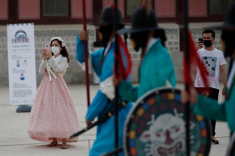 Visitors hold their smartphones while maintaining social distancing during a re-enactment ceremony of the changing of the Royal Guard at the Gyeongbok Palace in Seoul, South Korea. AP Photo