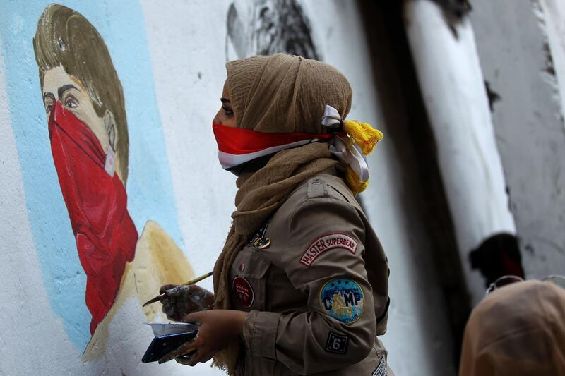 An Iraqi protester paints on a concrete barrier on Al Rasheed Street.  AFP