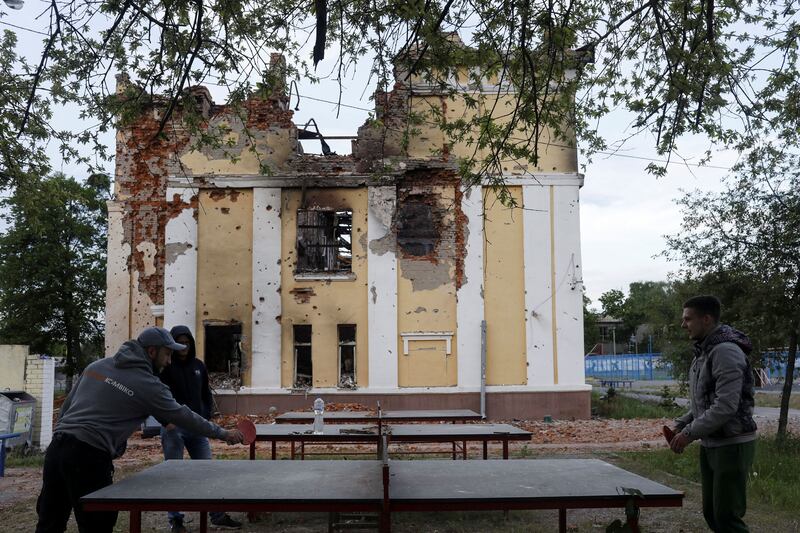 Former students play table tennis in the playground of a destroyed school in Kharkiv. Reuters