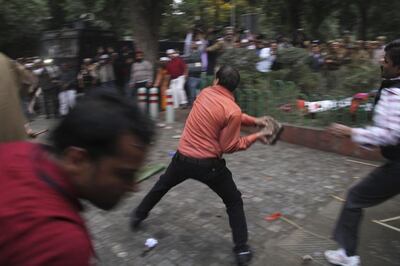 A BJP supporter throws rocks at supporters of Aam Aadmi Party outside the BJP office in New Delhi. AP