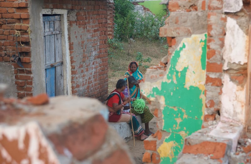 Former inhabitants of the of Podemepta village sit at an abandoned house. The houses once belonged to a prosperous fishermen community but are now a testimony of widespread devastation caused by climate change.