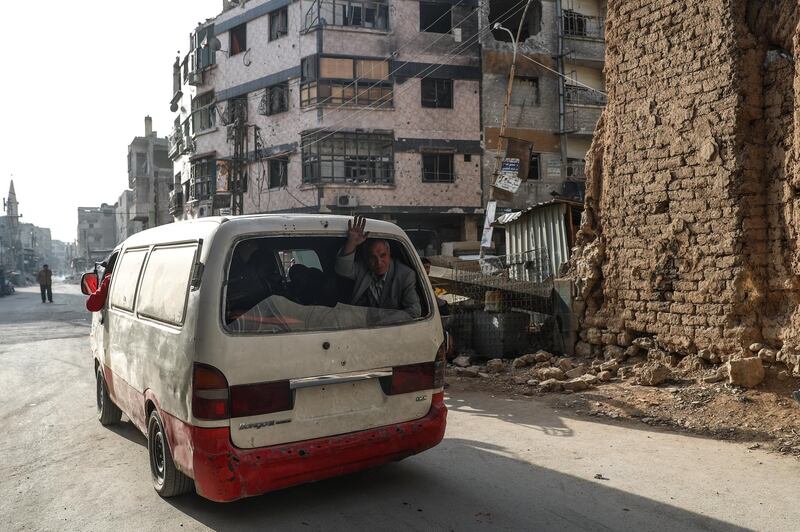 An elderly man waves from inside of a van as it departs during the evacuation in rebels-held Douma, Syria, on March 17, 2018. Mohammed Badra / EPA
