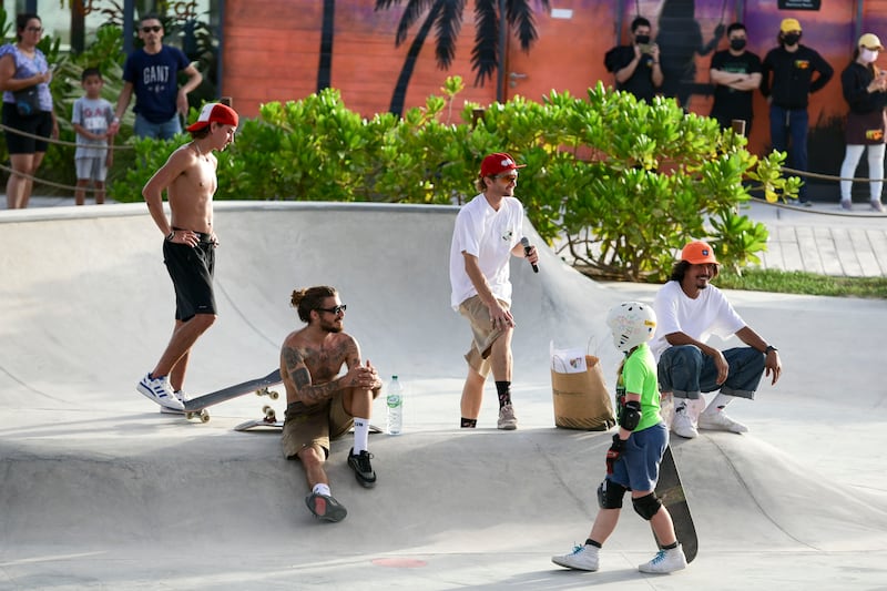 Some of the skateboarders take a rest on the skate bowl. 