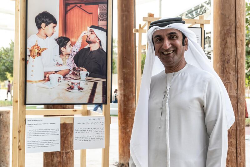 Issam Al Mulla stands next to the picture of him and his children at the exhibition.