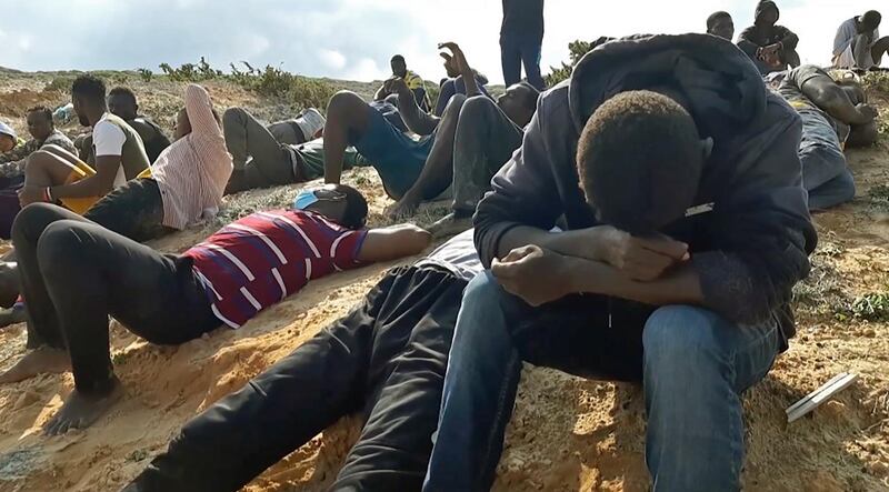 Migrant survivors of a deadly shipwreck sit on a sandy beach on the coast of al-Khums, a port city 120 kilometres  west of the Libyan capital Tripoli. AFP