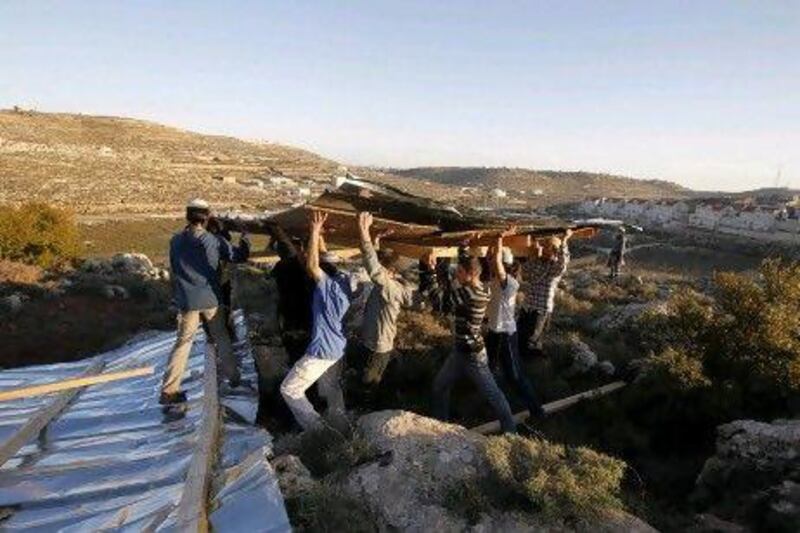 Jewish settlers carry planks as they build a makeshift structure at the unauthorised outpost of Mitzpe Avihainear the West Bank city of Hebron