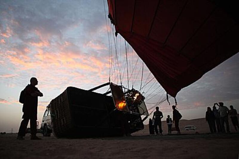 Hot air balloon pilot Peter Kollar, of Balloon Adventures Emirates, fills a balloon with hot air in the early morning desert light yesterday.