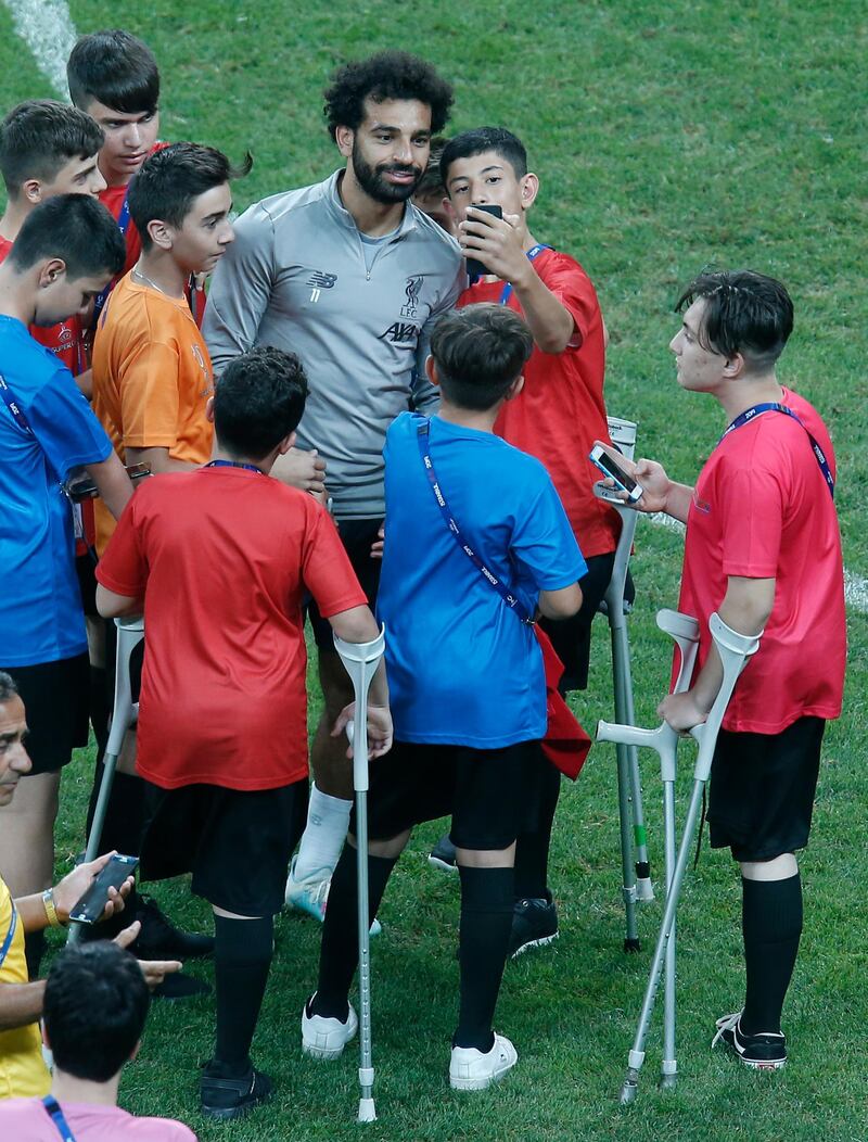 Liverpool's Mohamed Salah, poses for photos with children following a training session at the Besiktas Park Stadium, in Istanbul. AP Photo