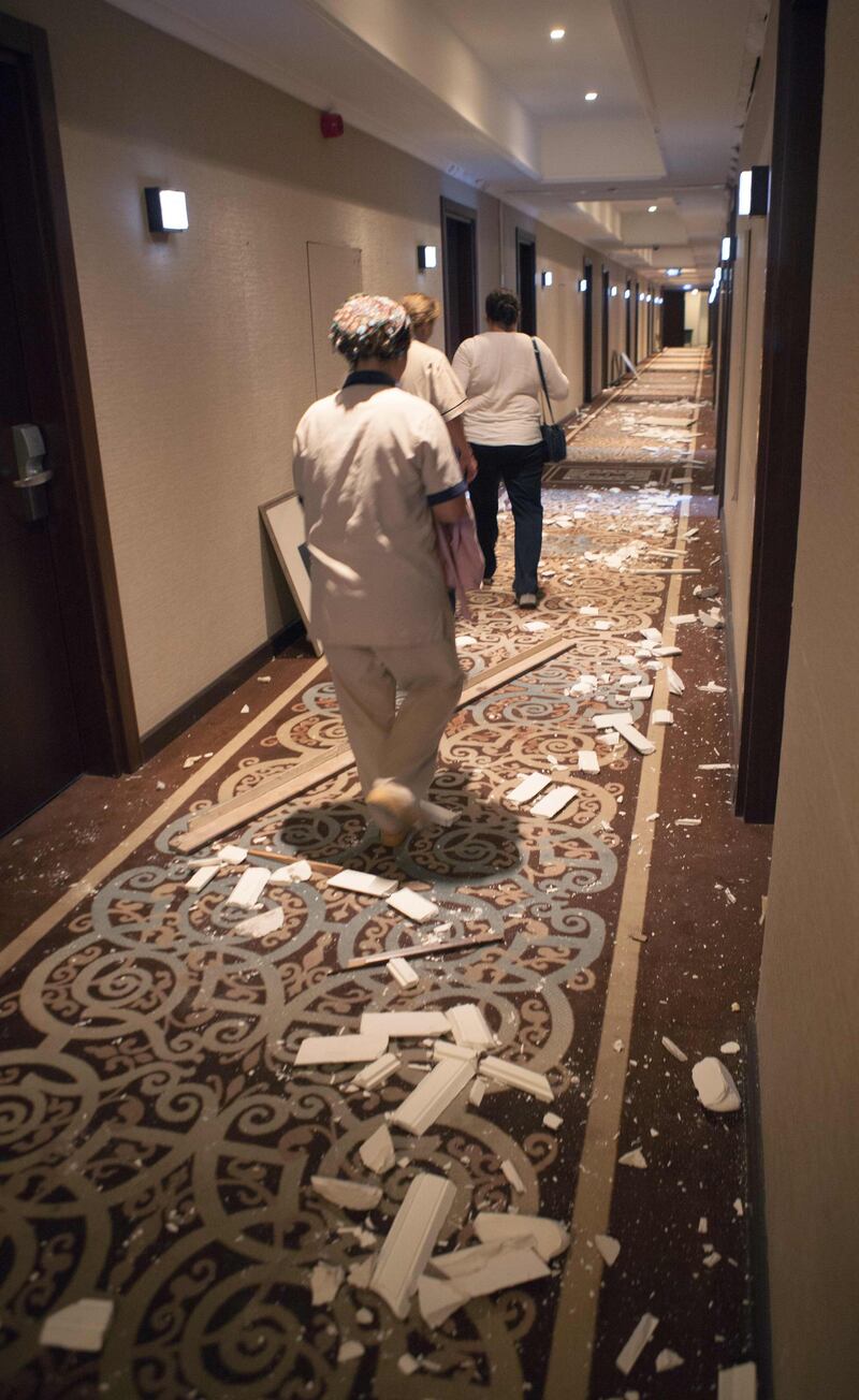 Workers at Acapulco hotel in Kyrenia (Girne) in the self-proclaimed Turkish Republic of Northern Cyprus (TRNC) north of the divided Cypriot capital Nicosia, assess the damage after the building was damaged when a military depot exploded nearby, on September 12, 2019. Multiple explosions at a Turkish military base in northern Cyprus damaged a hotel in a neighbouring holiday resort early Thursday, prompting the evacuation of terrified tourists, officials said. / AFP / Birol BEBEK
