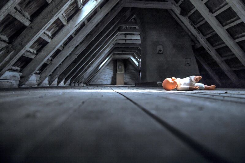 Doll lying at empty dark attic