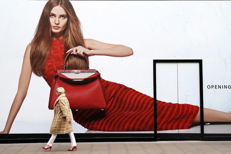 A woman walks past a giant advertising board outside a shop in central London. The British economy grew by 0.7 per cent in the final quarter of last year, its fastest pace since 2007. Facundo Arrizabalaga / EPA
