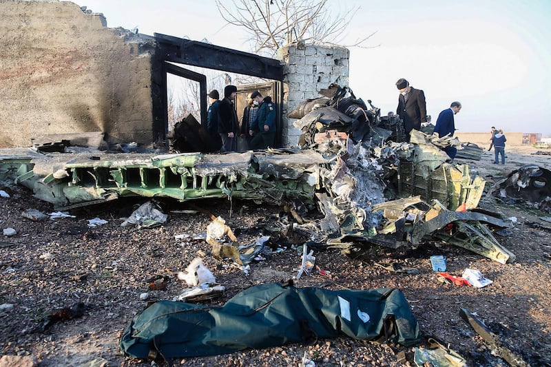 People stand near the wreckage after a Ukrainian plane carrying 176 passengers crashed near Imam Khomeini airport in Tehran on January 8, 2020. All 176 people on board a Ukrainian passenger plane were killed when it crashed shortly after taking off from Tehran on January 8, Iranian state media reported. State news agency IRNA said 167 passengers and nine crew members were on board the aircraft operated by Ukraine International Airlines. / AFP / ISNA / ISNA / ROHHOLLAH VADATI
