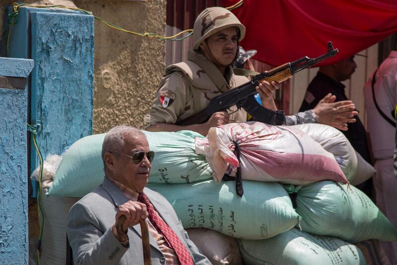 A resident sits next to a soldier guarding outside a polling station during second day of a referendum on draft constitutional amendments, in Cairo, Egypt. EPA