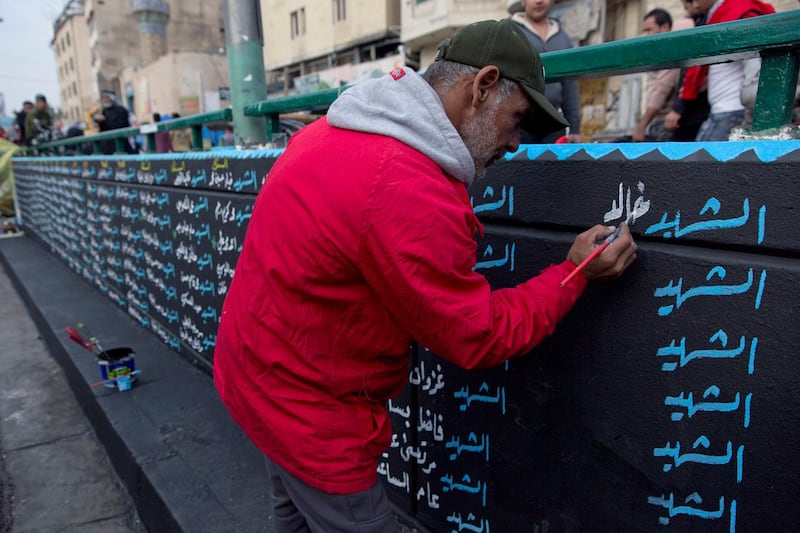 An activist works on a mural with names of protesters killed in the anti government demonstrationsr. AP Photo