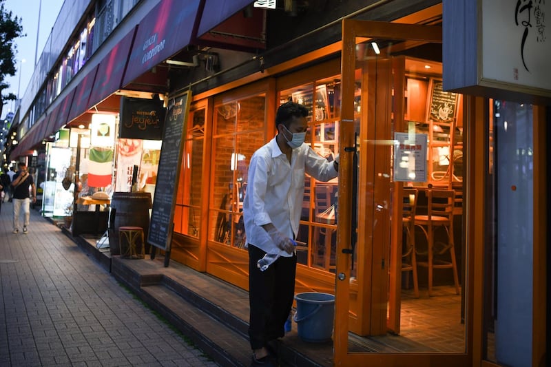 An employee wearing a protective mask cleans a entrance of a restaurant in Yurakucho district of Tokyo, Japan. Bloomberg
