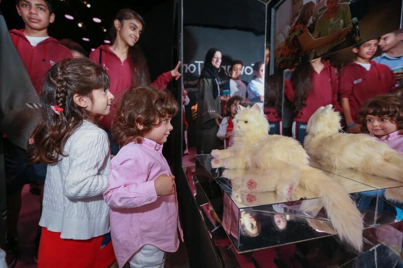 Girls in awe of the interactive cat which helps trauma victims heal through touch. Victor Besa for The National.