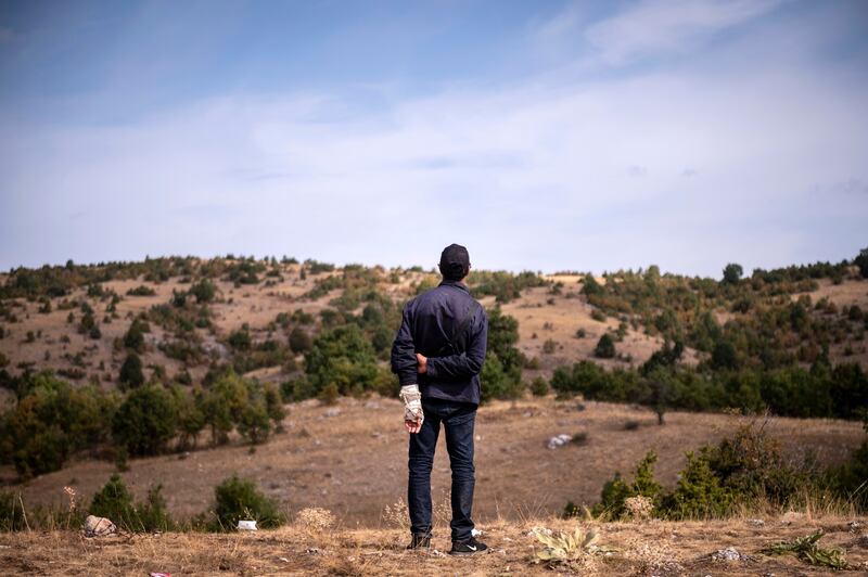 A migrant stands on a hill at an abandoned army outpost near Ieropigi village, northern Greece, at the Greek - Albanian border.
