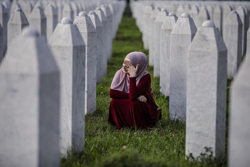 A Bosnian Muslim woman cries between graves of her father, two grandfathers and other close relatives, all victims of Srebrenica genocide, at the cemetery in Potocari near Srebrenica, Bosnia and Herzegovina. Getty Images