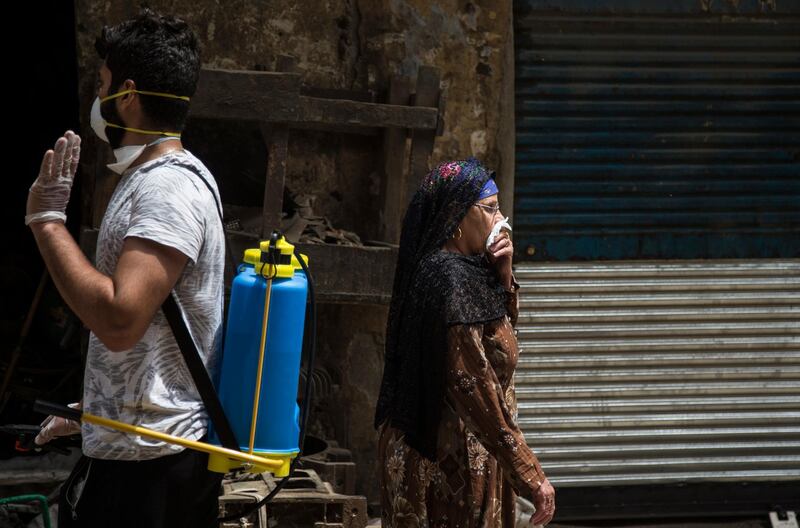 A woman covers her face during a civil initiative to sterilise garbage collectors' neighbourhood of 'The Zebaalin' to help stop the spread of coronavirus at Cairo, Egypt.  EPA