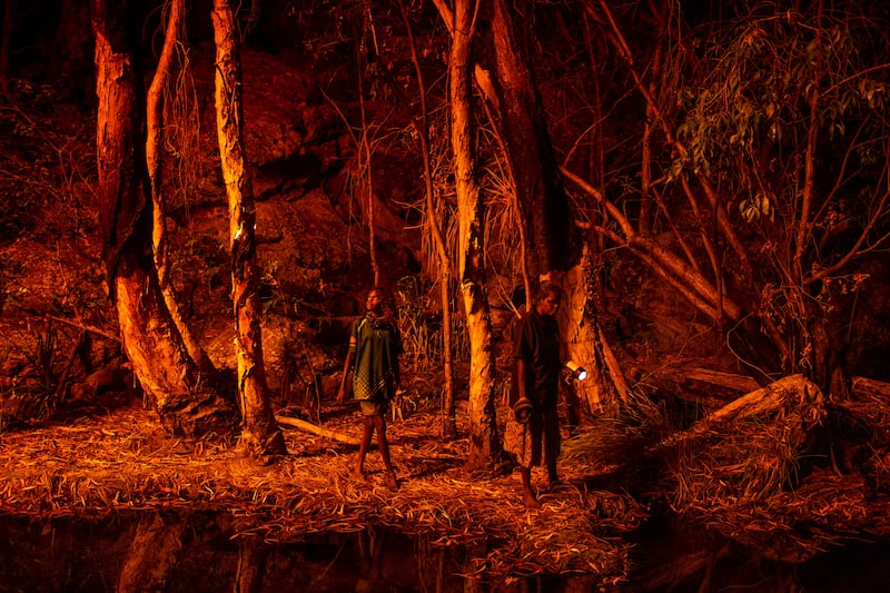 The photo which won the World Press Photo Story Of The Year award by Matthew Abbott for National Geographic Magazine/Panos Pictures, titled Saving Forests With Fire, shows Stacey Lee, 11-years-old, left, setting the bark of trees alight to produce a natural light source to help hunt for file snakes (Acrochordus arafurae), in Djulkar, Arnhem Land, Australia, on July 22, 2021. Matthew Abbott for National Geographic / Panos Pictures / World Press Photo