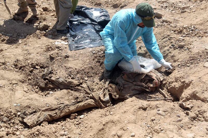 (FILES) In this file photo taken on April 12, 2015 A member of the Iraqi security forces wearing protective clothes inspects a mass grave containing the remains of dozens of people believed to have been slain by jihadists of the Islamic State (IS) group at the Speicher camp in the city of Tikrit. The Islamic State group left behind more than 200 mass graves in Iraq containing up to 12,000 victims that could hold vital evidence of war crimes, the UN said November 6, 2018.
The United Nations in Iraq (UNAMI) and its human rights office said they had documented a total of 202 mass graves in parts of western and northern Iraq held by IS between 2014 and 2017. / AFP / Ahmad AL-RUBAYE
