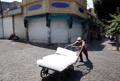 An Iranian worker pulls a cart next to closed shops around the Tehran's old grand bazaar in Tehran, Iran, 05 July 2021. EPA