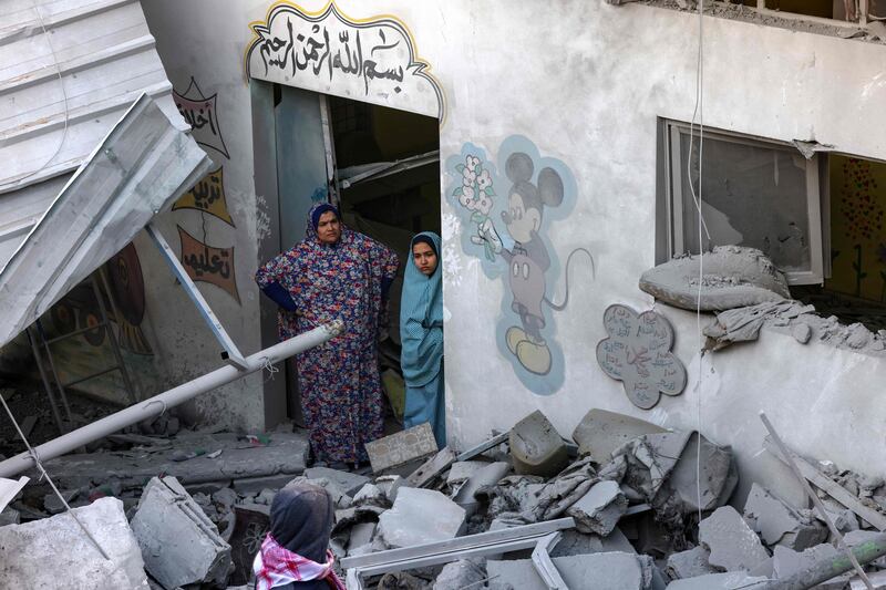 A woman and a child stand amid the rubble at a kindergarten hit by Israeli bombing in Rafah. AFP